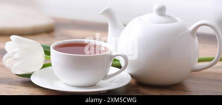 Teiera, tazza di bevanda calda e tulipani sul tavolo, primo piano Foto Stock