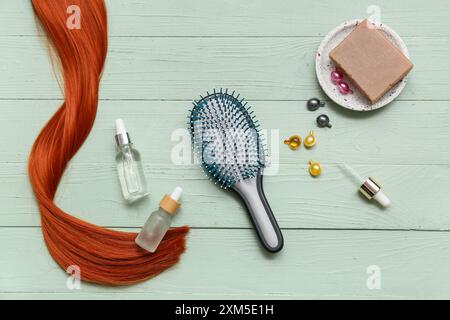 Filo di zenzero con spazzola, capsule, bottiglie di prodotti cosmetici e sapone su fondo verde in legno Foto Stock