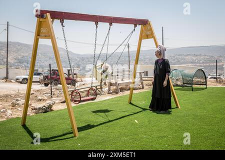 Palestina. 19 luglio 2024. La colona israeliana Techiya Chaim fa oscillare uno dei suoi dieci figli nell'avamposto di Evyatar. Nel luglio 2024, la Corte internazionale di giustizia ha annunciato, in un parere consultivo, che l'occupazione militare israeliana dei territori palestinesi era illegale e deve ritirarsi il più presto possibile. Ha elencato le violazioni del diritto internazionale come incluso il trasferimento di Israele dei coloni in Cisgiordania e il mantenimento della loro presenza. (Foto di Sally Hayden/SOPA Images/Sipa USA) credito: SIPA USA/Alamy Live News Foto Stock