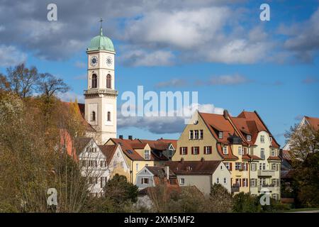 Ratisbona, Germania - 06 novembre 2023: Una torre dell'orologio si erge sopra case colorate a Ratisbona, Germania. Un cielo blu e soffici nuvole sbirciano Foto Stock