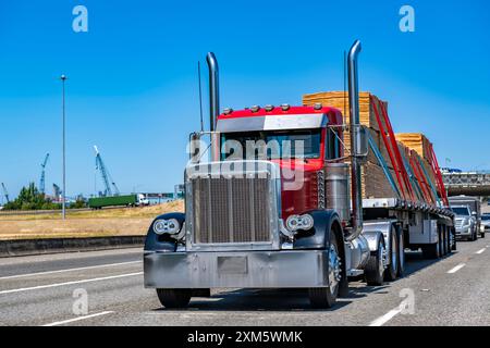 Carro industriale Day Cab rosso grande carro di perforazione trattore semi-motrice classico vecchio stile con parti cromate che trasportano compensato fissato su semirimorchio a pianale piatto r Foto Stock