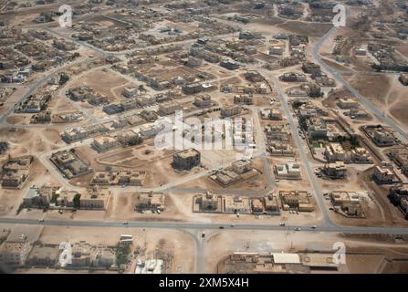Prospettiva aerea che mostra un vasto quartiere residenziale a Mascate, Oman, evidenziandone la disposizione, le strade e le strutture in un ambiente desertico Foto Stock