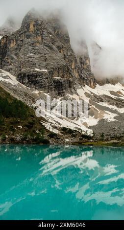 Il Lago di Sorapis risplende sotto l'imponente presenza del dito di Dio delle Dolomiti, offrendo un sereno panorama alpino Foto Stock