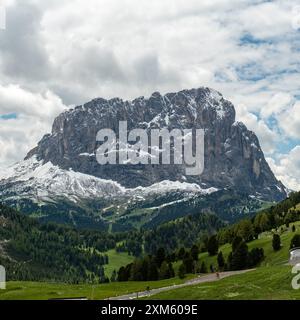 Nel periodo di transizione di giugno, Piz Culac si erge maestosamente ricoperto di neve, mentre il passo Gardena sottostante si irradia in un verde vivace, offrendo un'atmosfera suggestiva Foto Stock