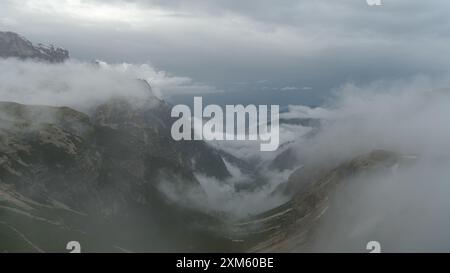 Giugno innevato sul circuito tre Cime Circuit Trail con cime dolomitiche che emergono dalla nebbia. Foto Stock
