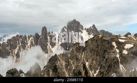 Il tempo imprevedibile di giugno sul circuito tre Cime: Neve e nebbia avvolgono le maestose cime dolomitiche Foto Stock