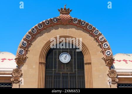 Tarragona, Spagna - 14 luglio 2024: Vista dettagliata dell'orologio e degli elementi decorativi sulla facciata del mercato centrale. Foto Stock