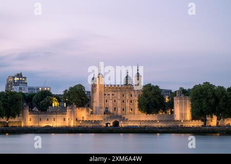 Mentre il sole tramonta sulla storica Torre di Londra, il cielo pastello crea uno sfondo affascinante, a complemento della bellezza architettonica Foto Stock