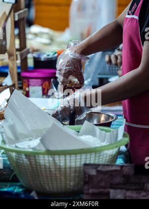 Un venditore che indossa i guanti prepara il cibo in uno stand di cibo di strada Foto Stock