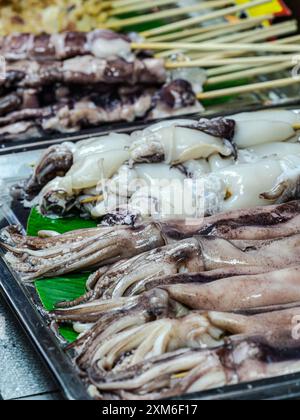 Calamari e seppie esposti sugli spiedini in una bancarella del mercato. Foto Stock