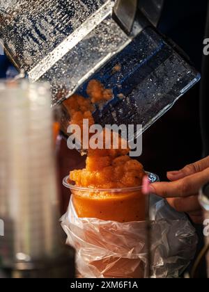 Frullato arancione versato nel bicchiere Foto Stock