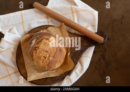 Pane a lievitazione naturale appena sfornato su un asse di legno Foto Stock