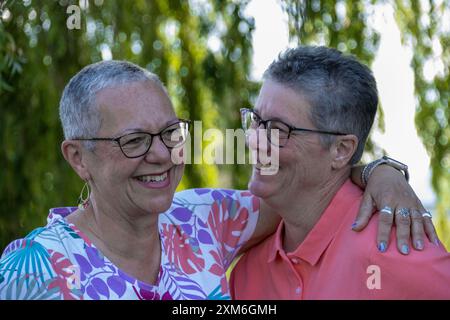 Felice coppia gay più anziana sorridente e abbracciante all'aperto Foto Stock