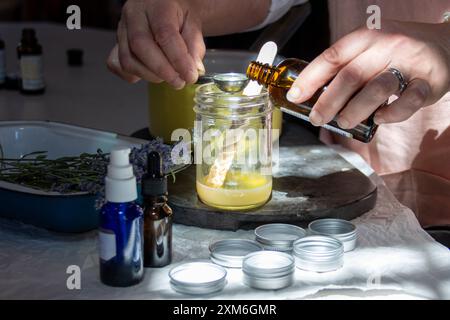 Mani che preparano il rimedio a base di erbe in un recipiente con oli essenziali Foto Stock