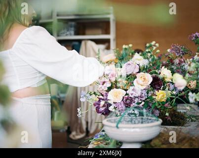 Donna che organizza un mazzo di fiori colorato in un laboratorio Foto Stock