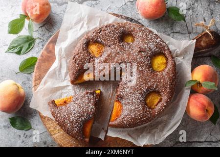 Delizioso brownie di pesca al cacao o torta di spugne di pesca al cioccolato primo piano su un tavolo di legno. Vista dall'alto orizzontale Foto Stock
