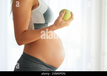 Gravidanza, donna e mela per stomaco in casa, maternità e dieta sana per nutrizione fetale. Sviluppo della gravidanza, spuntino prenatale e fibra per Foto Stock