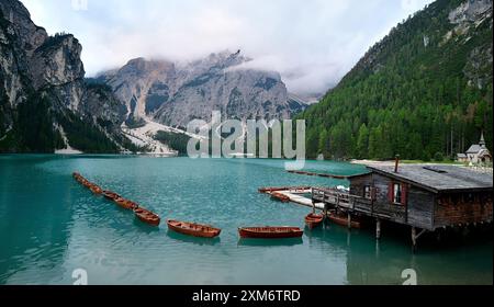 Lago Braies al mattino presto, carrozza su palafitte, barche a remi allineate, Cappella della Vergine Maria sul bordo del lago di montagna. Dolomiti, S. Foto Stock