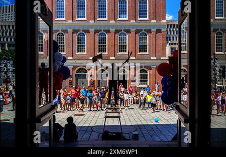 Boston, Massachusetts, Stati Uniti - 2 luglio 2024: Giocoliere che si esibisce di fronte a una grande folla. Vista in silhouette dall'interno del Quincy Market, un quartiere storico Foto Stock