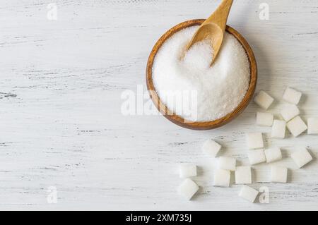Cospargere di zucchero bianco granulato in cucchiaio e recipiente con cubetti di zucchero Foto Stock