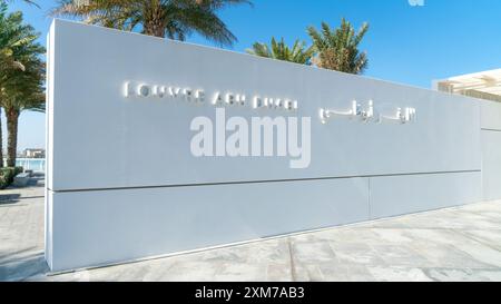 Abu Dhabi, Emirati Arabi Uniti - 18 febbraio 2021: Insegna del museo del Louvre Abu Dhabi su una parete bianca all'ingresso principale dell'isola di Saadiyat. Foto Stock