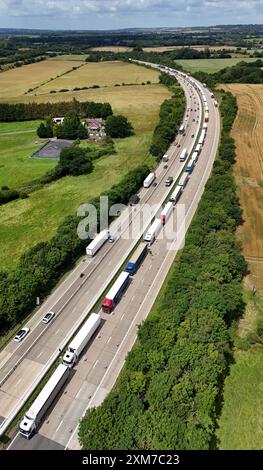 Gli autocarri fanno la fila per attraversare la Manica verso l'Europa durante l'operazione Brock sulla M20 vicino ad Ashford nel Kent, mentre inizia l'affollato periodo estivo dei viaggi. I conducenti sono avvertiti di aspettarsi un "fine settimana di guai" sulle strade, mentre milioni di famiglie si imbarcano in viaggi di fuga dopo che molte scuole in Inghilterra e Galles si sono sciolte per l'estate di questa settimana. Data foto: Venerdì 26 luglio 2024. Foto Stock