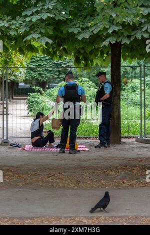 La polizia chiede a una donna di lasciare il suo posto da picnic nei giardini delle Tuileries a causa delle misure di sicurezza per le Olimpiadi. Parigi, Francia, 22 luglio 2024 Foto Stock