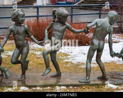 Narvik, Norvegia - marzo 2023 - bambini che giocano la statua, Statua dei bambini che tengono per mano Trygve Thorsen 1962. Città di ​​park Torvet in inverno. Nord Foto Stock