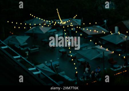 Luci sfocate della ghirlanda adagiate sulla terrazza, sul patio del ristorante in serata o di notte dall'alto. Decorazioni natalizie per una festa. Ghirlande astratte Foto Stock