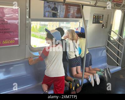 Durante l'estate a Brooklyn, New York, i bambini guardano fuori dalla finestra della metropolitana sulla strada per Coney Island. Foto Stock