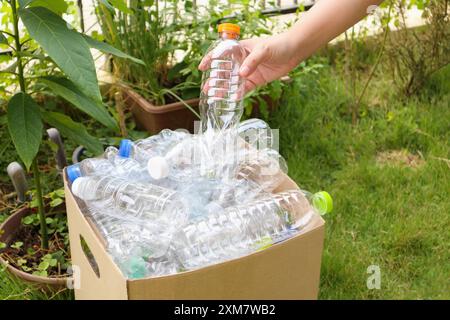 Tenere le mani e inserire i flaconi di plastica nella scatola marrone per rifiuti Foto Stock