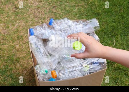 Tenere le mani e inserire i flaconi di plastica nella scatola marrone per rifiuti Foto Stock