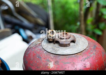 Una valvola della bombola di gas rotta giace su una bombola rossa. Pericolo di perdite di gas ed esplosioni. Copia spazio per il testo Foto Stock