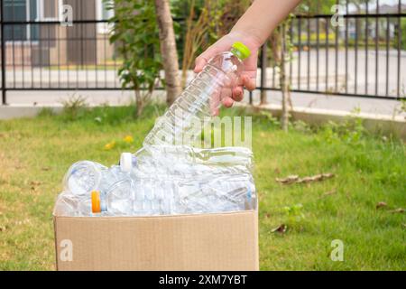 Tenere le mani e inserire i flaconi di plastica nella scatola marrone per rifiuti Foto Stock