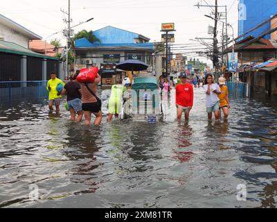 Malabon City, Filippine. 24 luglio 2024. La gente attraversa una strada allagata. Il tifone carina (nome internazionale, Gaemi) dà un'enorme quantità di pioggia torrenziale che colpisce il paese aumentando il livello dell'acqua e causando danni diffusi ai filippini. (Immagine di credito: © Josefiel Rivera/SOPA Images via ZUMA Press Wire) SOLO PER USO EDITORIALE! Non per USO commerciale! Foto Stock