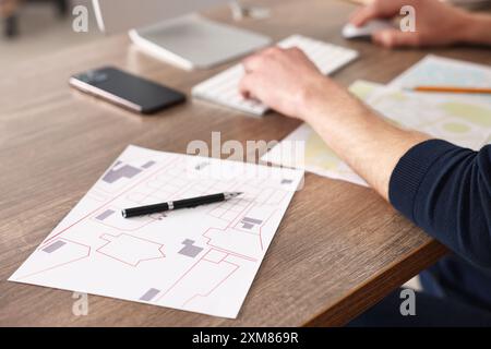 Cartografo che lavora con mappe catastali al tavolo di legno in ufficio, primo piano Foto Stock