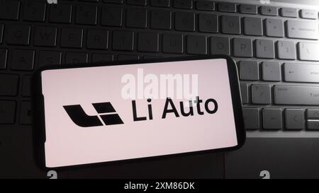In questa illustrazione fotografica, il logo li Auto viene visualizzato su uno smartphone con una tastiera per laptop sullo sfondo. Foto Stock