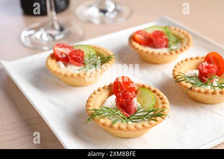 Stuzzichini deliziosi con salsicce affumicate secche, formaggio spalmabile e verdure su un tavolo di legno, primo piano Foto Stock