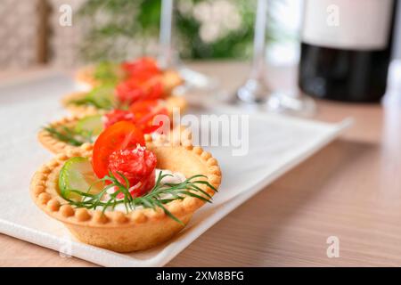 Stuzzichini deliziosi con salsicce affumicate secche, formaggio spalmabile e verdure su un tavolo di legno, primo piano Foto Stock