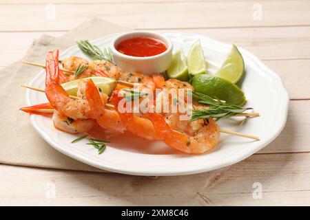 Spiedini con deliziosi gamberetti alla griglia serviti su un tavolo di legno Foto Stock