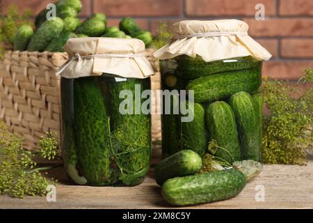 Cetrioli sottaceto in barattoli e aneto su tavola di legno, primo piano Foto Stock