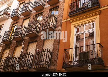 Madrid, Spagna 1 luglio 2024 contrasto di diversi stili architettonici. Edificio restaurato in mattoni marroni, vecchio balcone giallo su una vecchia strada Foto Stock