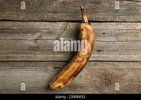 Banana troppo matura con macchie scure sul tavolo di legno, vista dall'alto Foto Stock