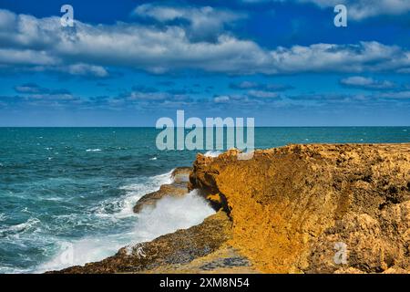 Onde che si infrangono su un promontorio di roccia rossa nell'Oceano Indiano a Point Quobba, una parte remota della costa corallina dell'Australia Occidentale a sud di Carnarvon Foto Stock