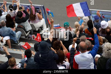 Parigi, Francia. 26 luglio 2024. Gli spettatori ondeggiano le bandiere mentre le squadre si dirigono lungo la Senna, durante la cerimonia di apertura dei Giochi Olimpici di Parigi 2024. Crediti: Isabel Infantes/Alamy Live News Foto Stock