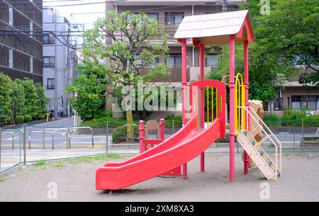 Lo scivolo rosso gioioso per bambini e bambini nel parco giochi residenziale giapponese Foto Stock