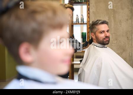 Padre e figlio passano del tempo insieme a prendere appuntamento con il parrucchiere Foto Stock