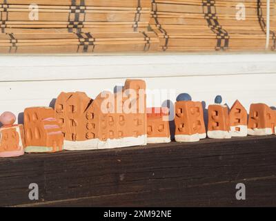 Case in miniatura in terracotta in ceramica su davanzale con cieco avvolgibile in bambù in Sardegna, Italia. Primo piano orizzontale. Foto Stock