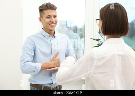 Uomo e donna che usano il linguaggio dei segni per comunicare al chiuso Foto Stock