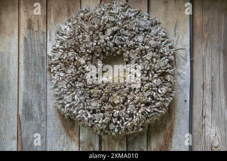 Ghirlanda di porte in materiali naturali di fronte a un muro di legno, Muensterland, Renania settentrionale-Vestfalia, Germania Foto Stock